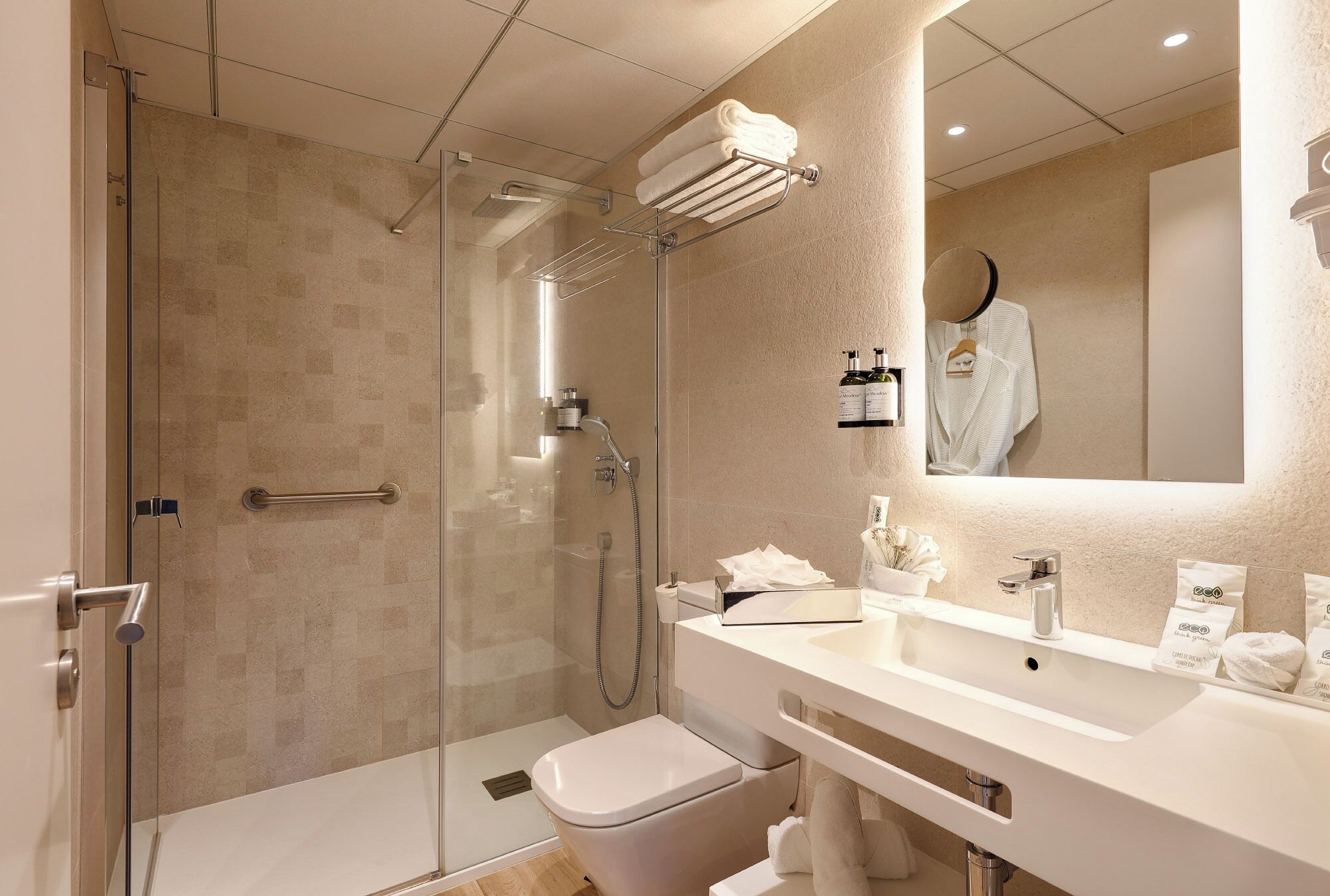 Une salle de bain moderne avec une douche à parois de verre, un lavabo blanc et un miroir au-dessus.