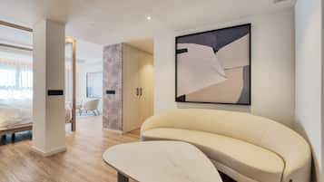 A modern hotel room with a sofa, a bed, a large abstract painting, and a minimalist design.