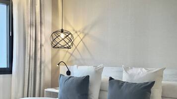 Un dormitorio moderno con una cama, dos almohadas, una mesita de noche y una lámpara colgante.