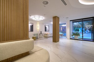 Een moderne lobby met een zithoek, een receptiebalie en een grote glazen deur naar buiten.