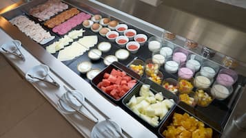 Een buffet met diverse gerechten, waaronder vleeswaren, kazen, fruit en desserts.