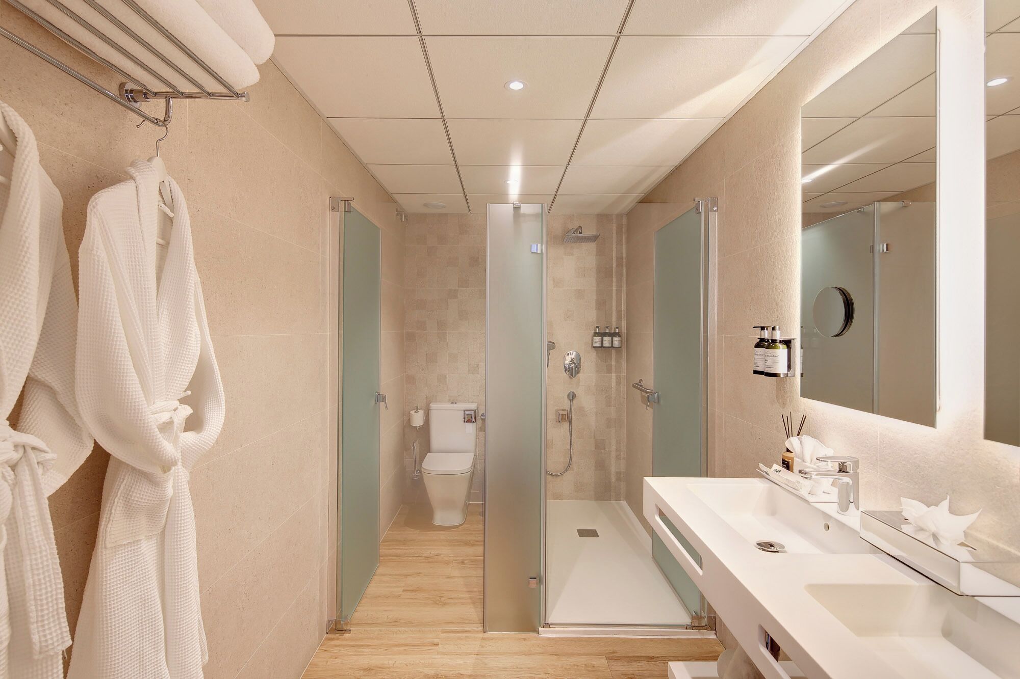 Une salle de bain moderne avec une douche à parois de verre, un grand miroir et un plancher en bois.