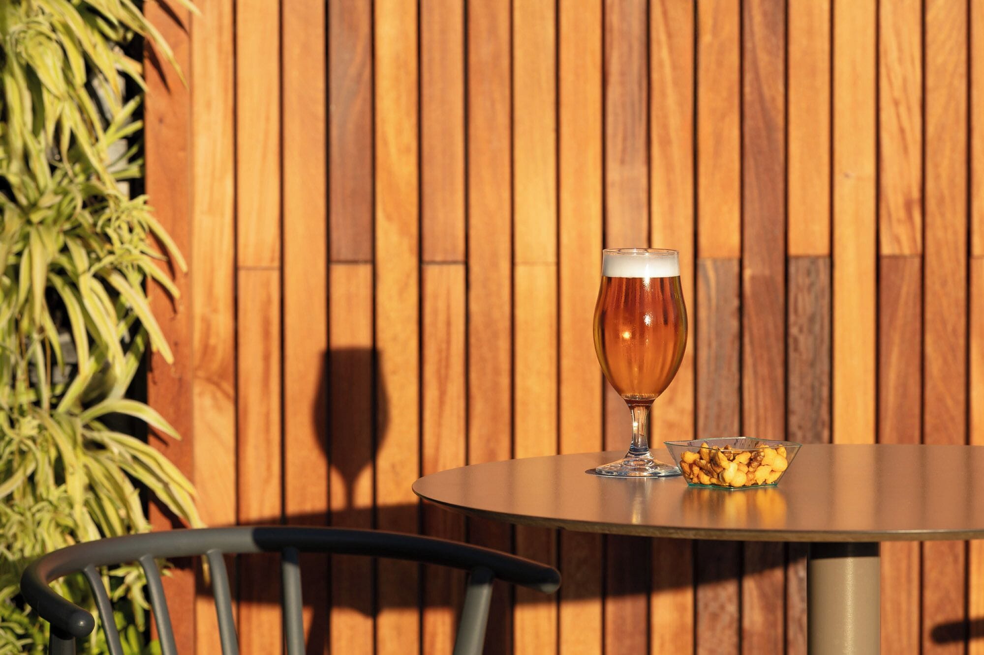 A round table with a glass of beer and a bowl of snacks.
