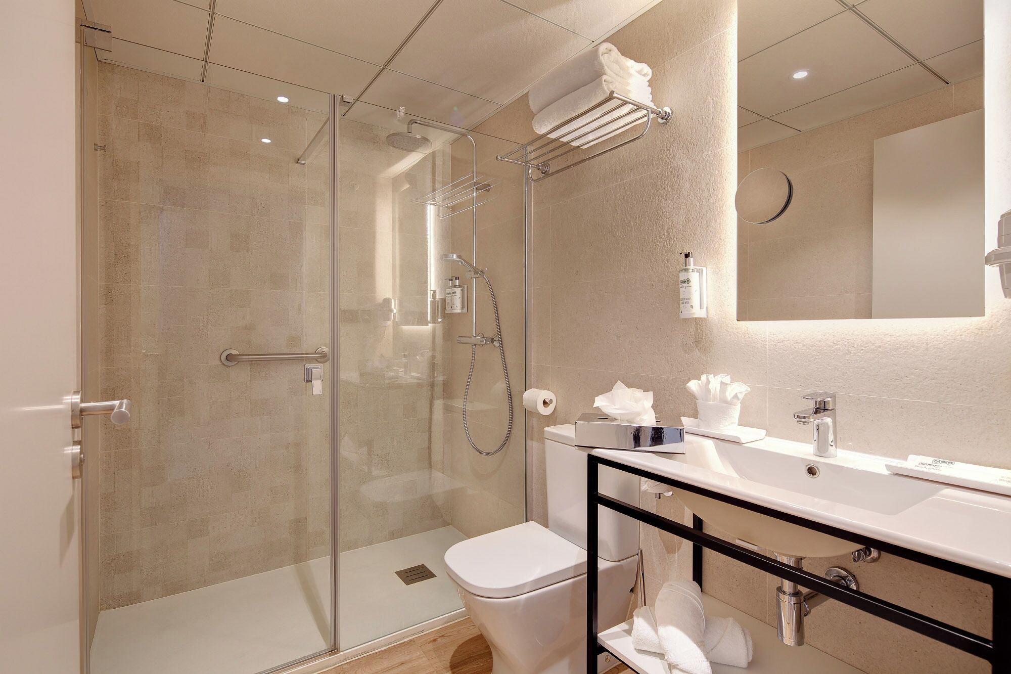 Un baño moderno con ducha envuelta en vidrio, inodoro blanco y tocador con espejo y lavabo.