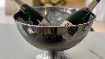 Un cuenco metálico contiene dos botellas de champán con etiquetas, sobre una superficie blanca.