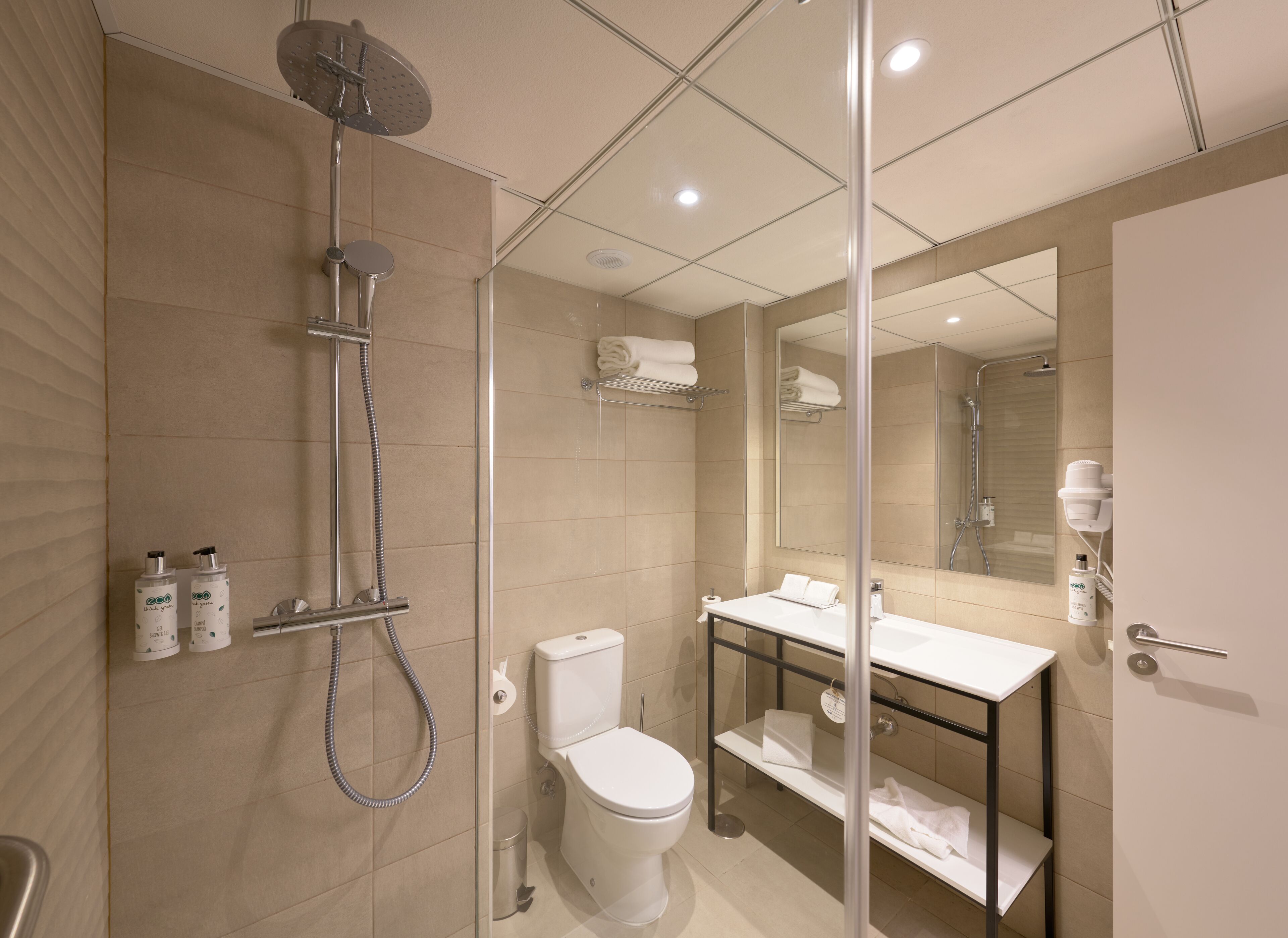 Un baño moderno con ducha acristalada, inodoro y tocador con espejo.