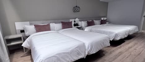 Une chambre d’hôtel moderne avec deux grands lits, une table de chevet, une lampe et un luminaire au plafond.