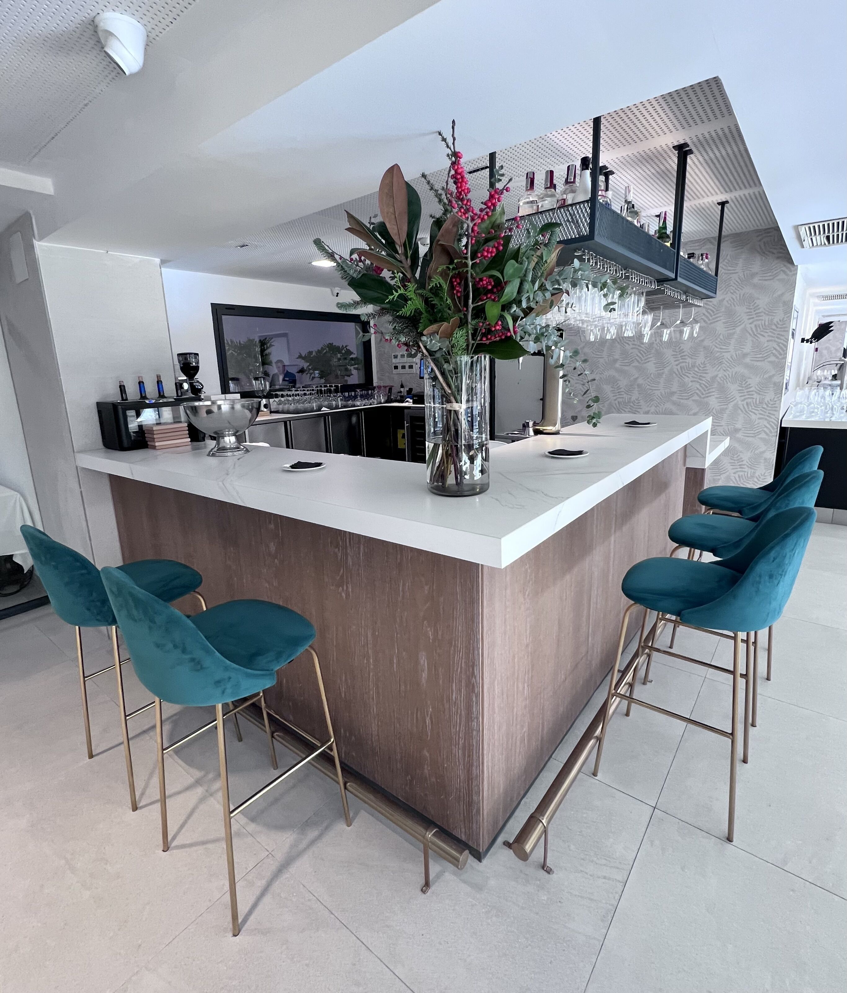 Una cocina moderna con una isla central, taburetes de bar y un jarrón decorativo con flores.