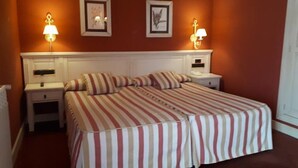 A hotel room with a large bed, two bedside tables, and two wall-mounted lamps. - Hotel Leonor Miron (Soria)