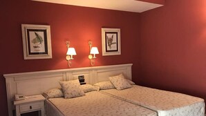 A double bed with a white bedspread, two bedside tables with lamps, and two framed botanical prints on the wall. - Hotel Leonor Miron (Soria)