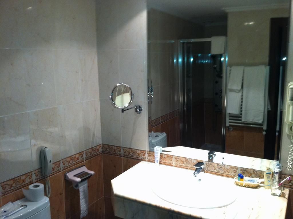 A bathroom with a sink, mirror, toilet, and shower.