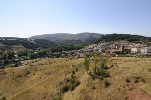 Un pueblo rural con edificios, un río y colinas al fondo.