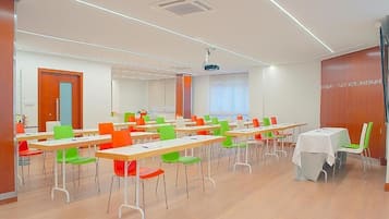 A conference room with multiple tables and chairs, a projector, and a whiteboard.