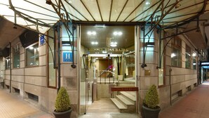 The entrance to Hotel Rias Baixas with a glass door, a staircase leading inside, and two potted plants at the entrance. - Rias Bajas (Pontevedra)