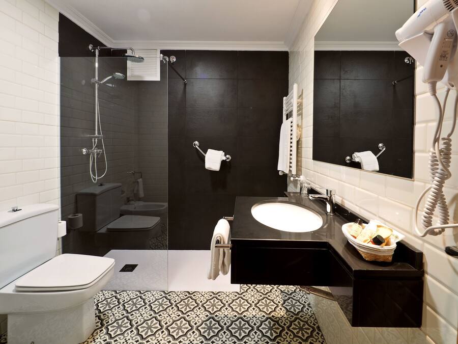 A modern bathroom with a toilet, bidet, shower, and sink.