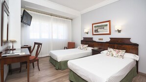 A hotel room with two beds, a desk with a chair, a TV, and a painting on the wall. - Rias Bajas (Pontevedra)