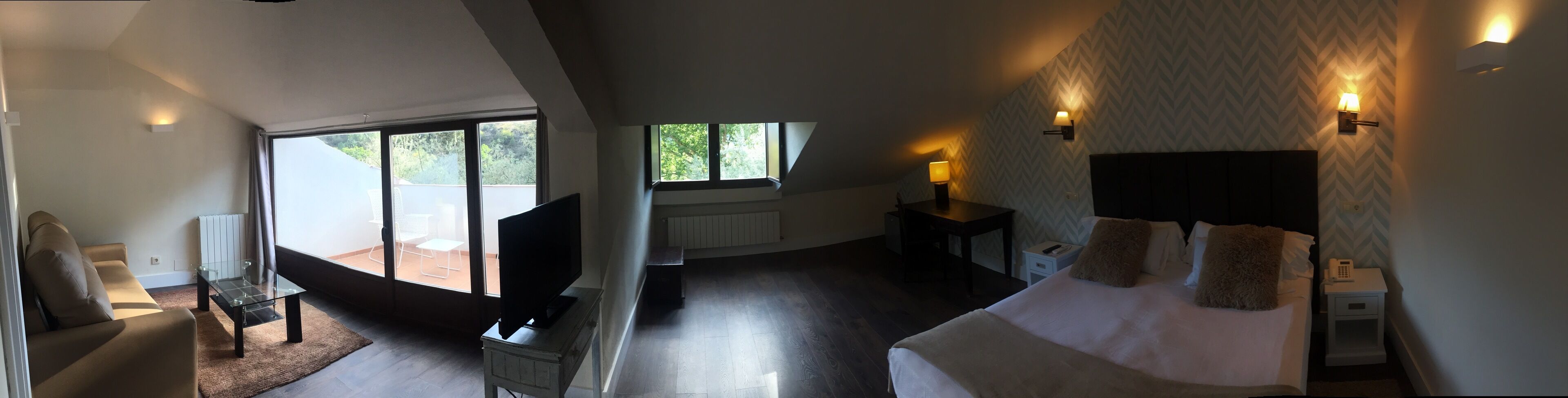 Un dormitorio con cama, mesitas de noche, televisión y ventana.