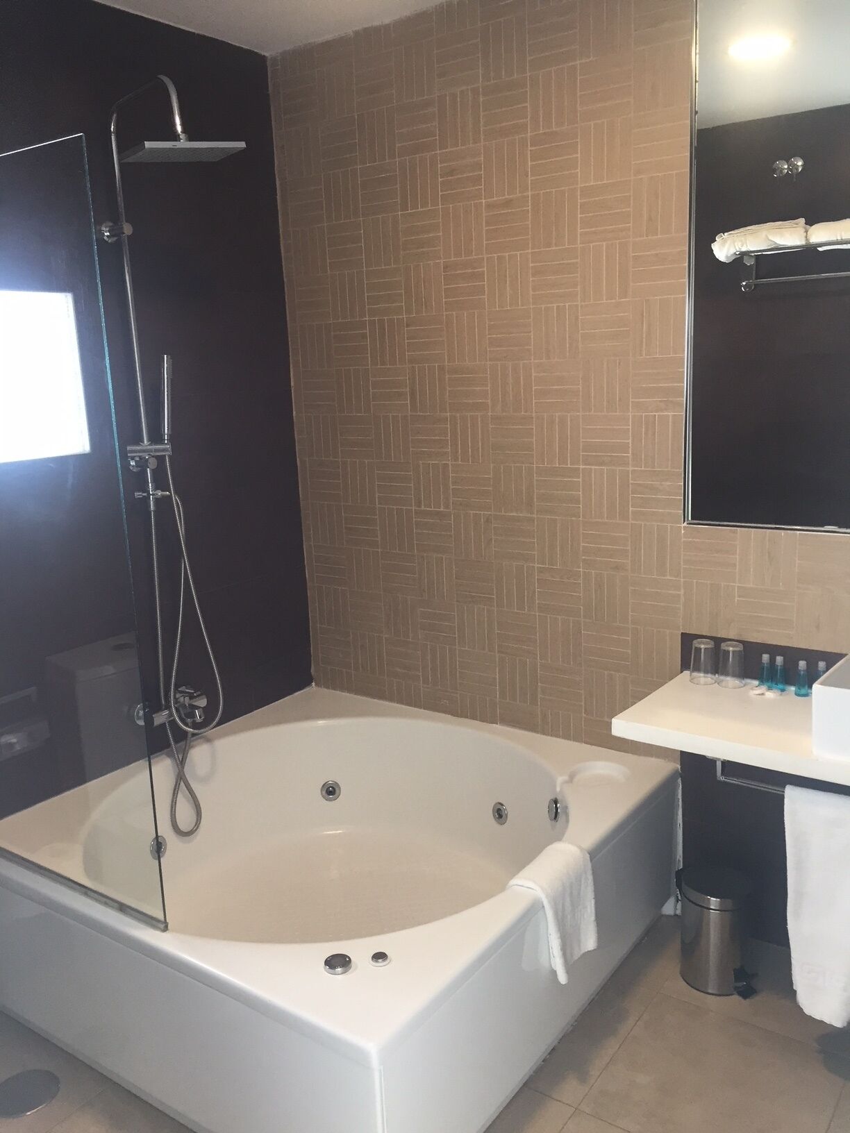 A modern bathroom with a freestanding bathtub, a showerhead, a sink with a mirror, and a towel rack.