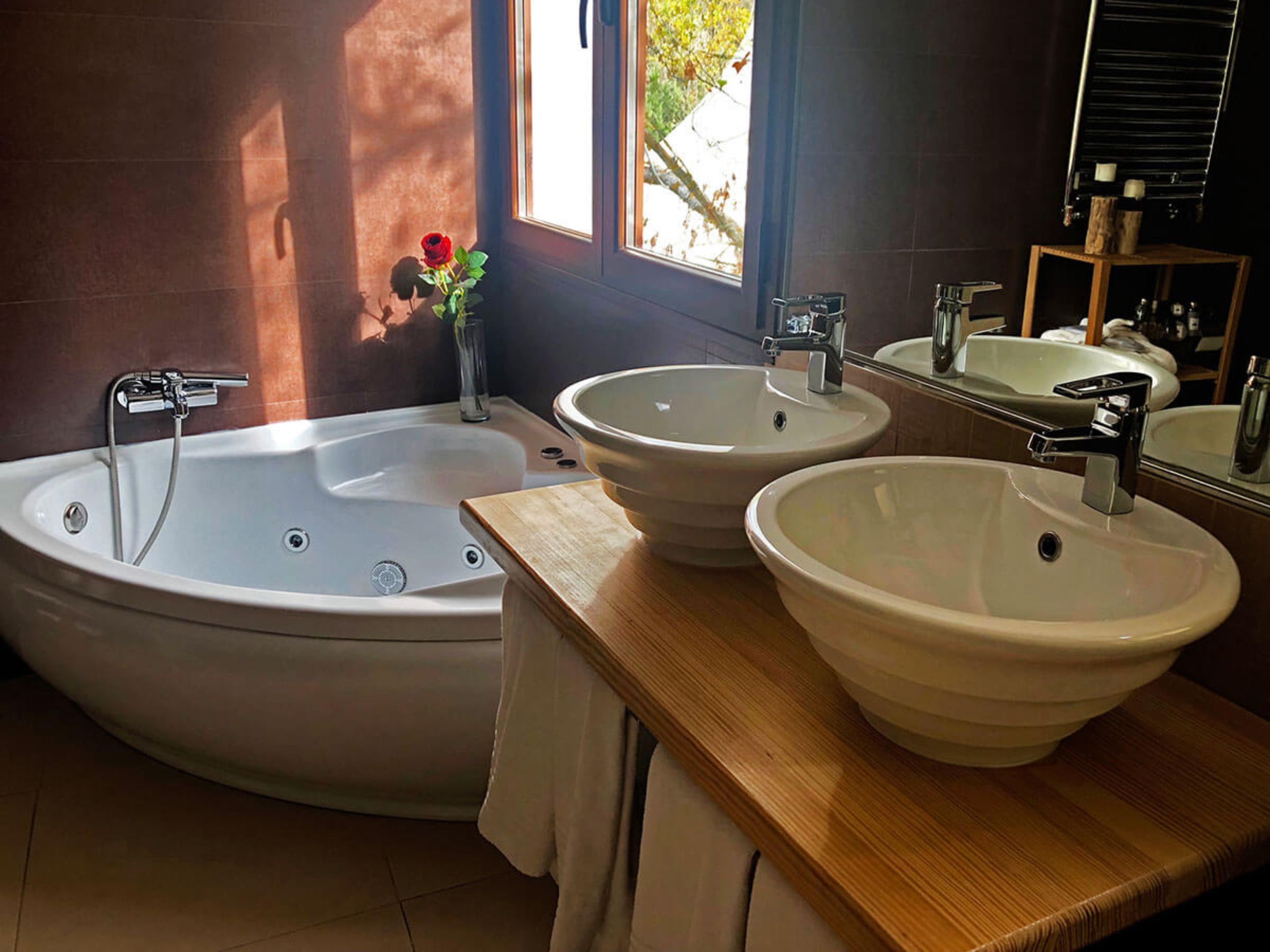 Un baño moderno con una bañera independiente, dos lavamanos y un espejo grande.