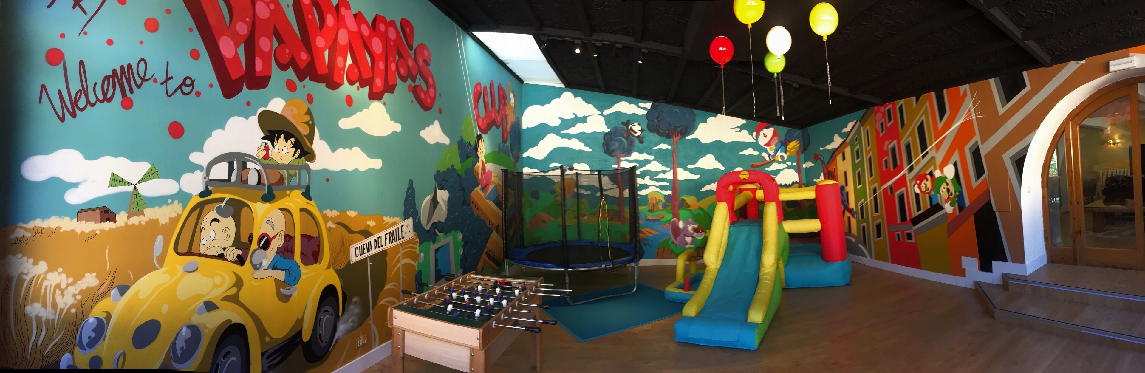 A children's play area with a foosball table, a trampoline, and colorful murals.