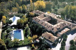Vista aérea de una extensa propiedad con varias construcciones, piscina y zonas verdes circundantes.
