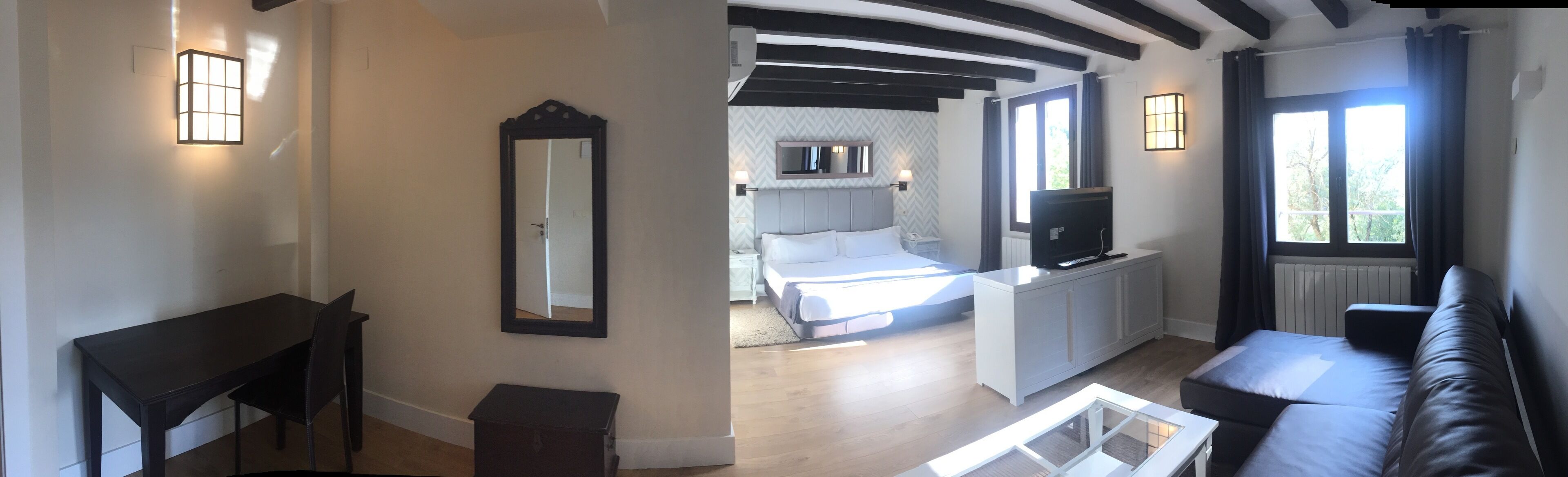Une chambre moderne avec un lit, une télévision et un canapé.