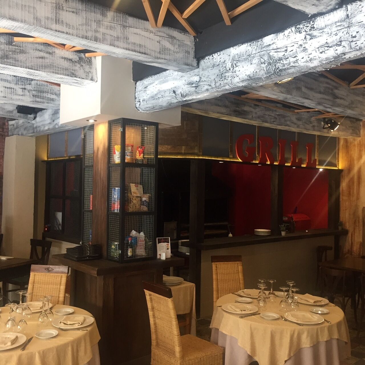 Ein Restaurantinneres mit runden Tischen, einer Grillstation und einer Kühlvitrine mit Speisen.