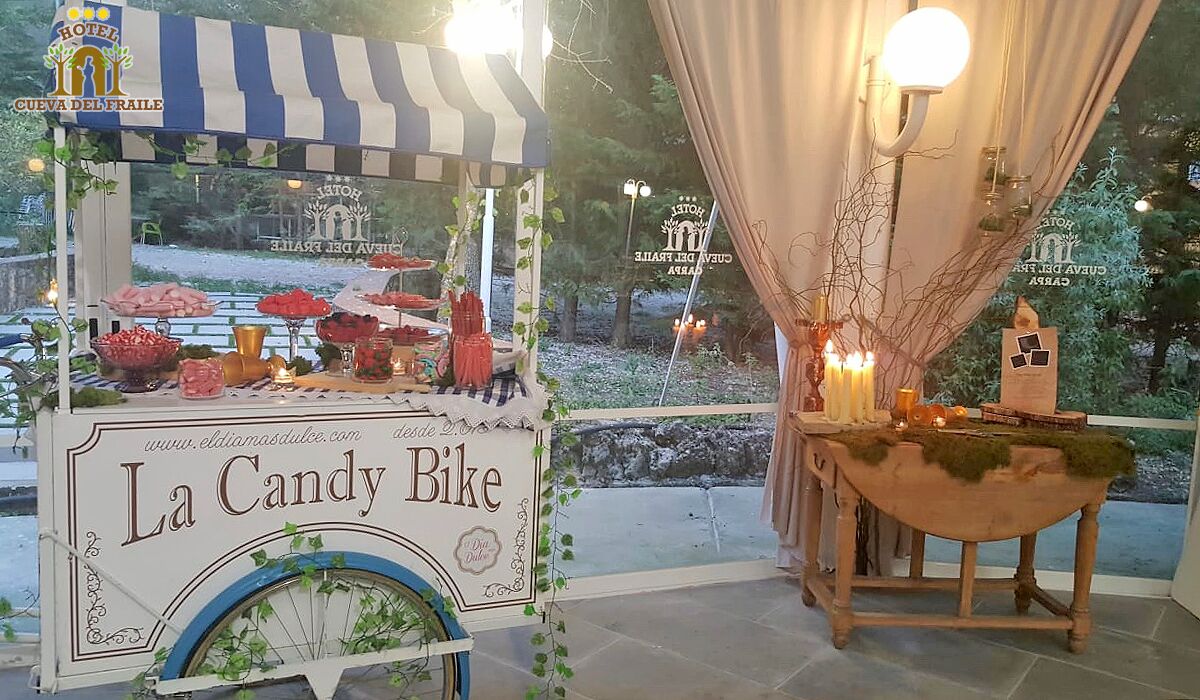 A La Candy Bike kiosk with a variety of sweets and a small table with candles and a lantern.