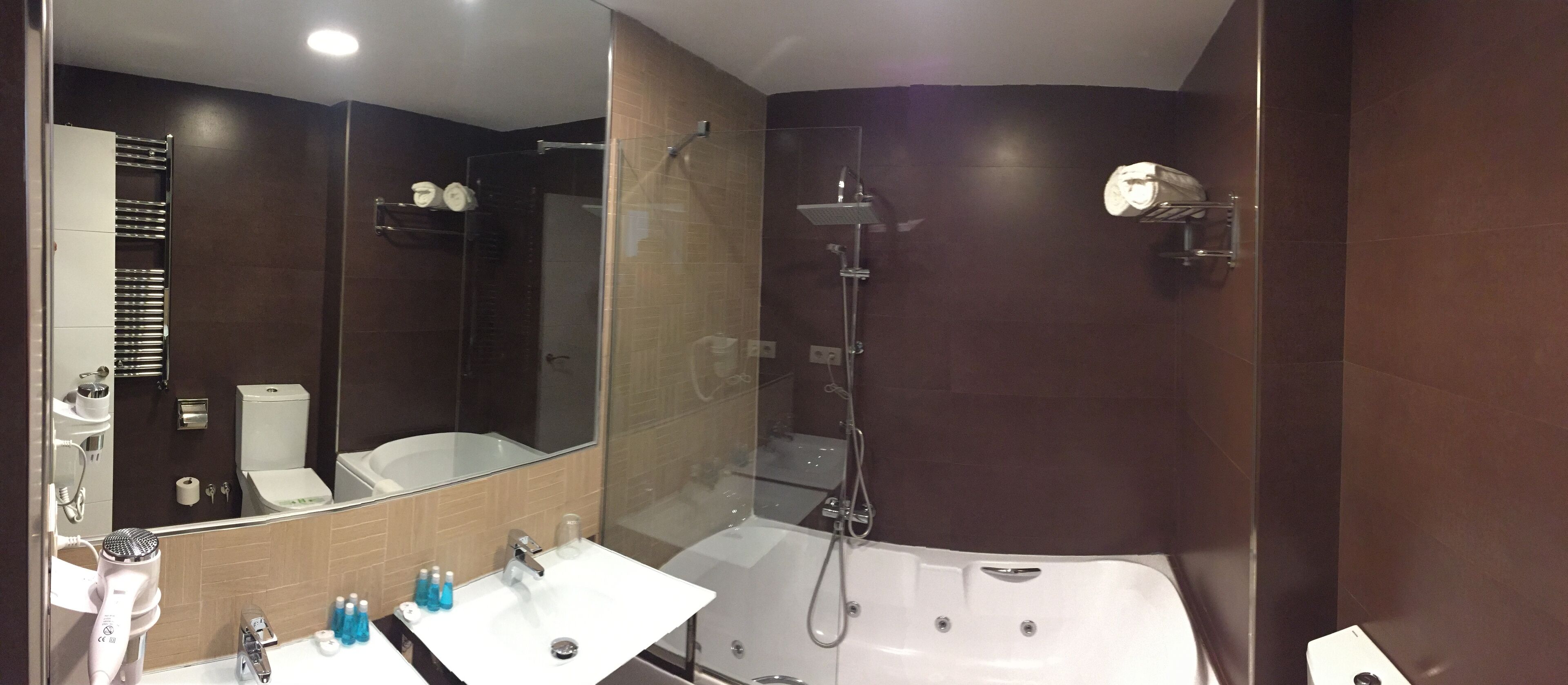 Une salle de bain moderne avec un grand miroir, deux lavabos, une douche et une baignoire.