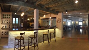Eine Bar mit Holzhockern, einer Weinauslage und einer rustikalen Decke.