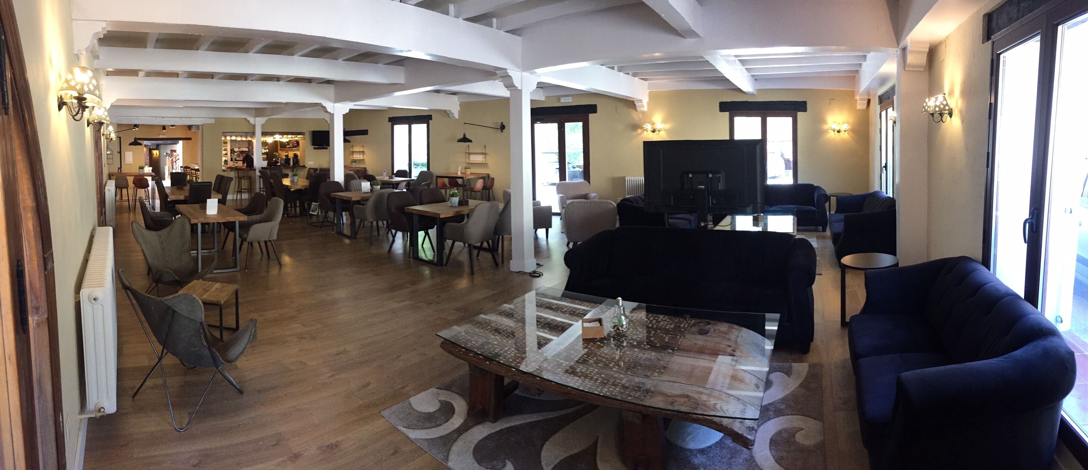 Amplia sala de estar con un sofá grande, una mesa de centro y una televisión. Se ofrecen diversas disposiciones de asientos y se observa un comedor al fondo.