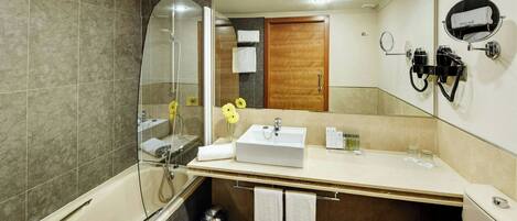 A modern bathroom with a glass-enclosed shower, a sink with toiletries, and a mirror with a hairdryer.