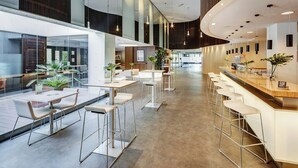 Un interior moderno con una zona de bar, asientos y plantas en macetas.