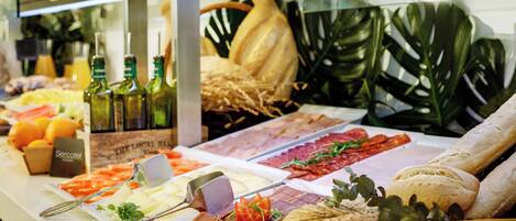 Un bufé con diversas opciones de comida, incluyendo carnes, quesos y pan.