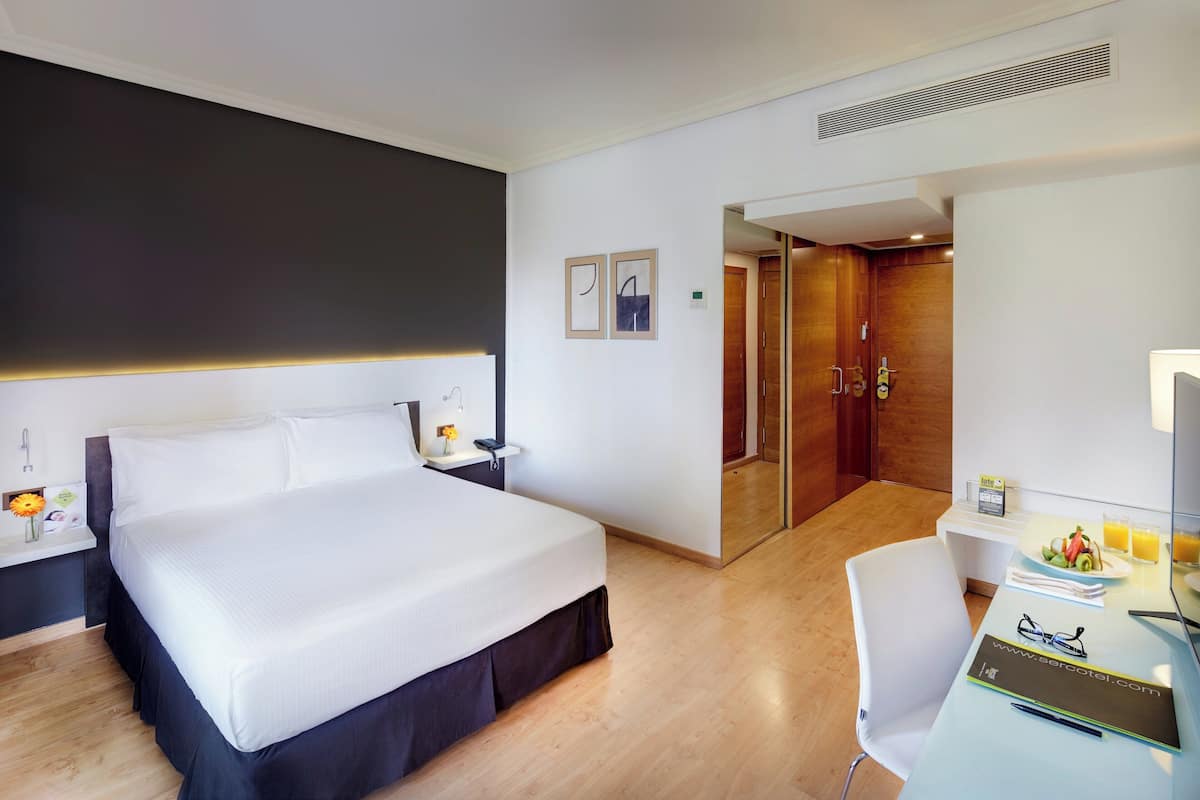 Habitación clásica | Edredón, minibar, caja de seguridad en la habitación y escritorio