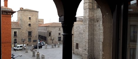 Un patio con edificios de piedra, una furgoneta blanca y una persona caminando.
