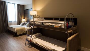 Habitación de hotel con dos camas, una mesita de noche con lámpara y una ventana con cortinas.