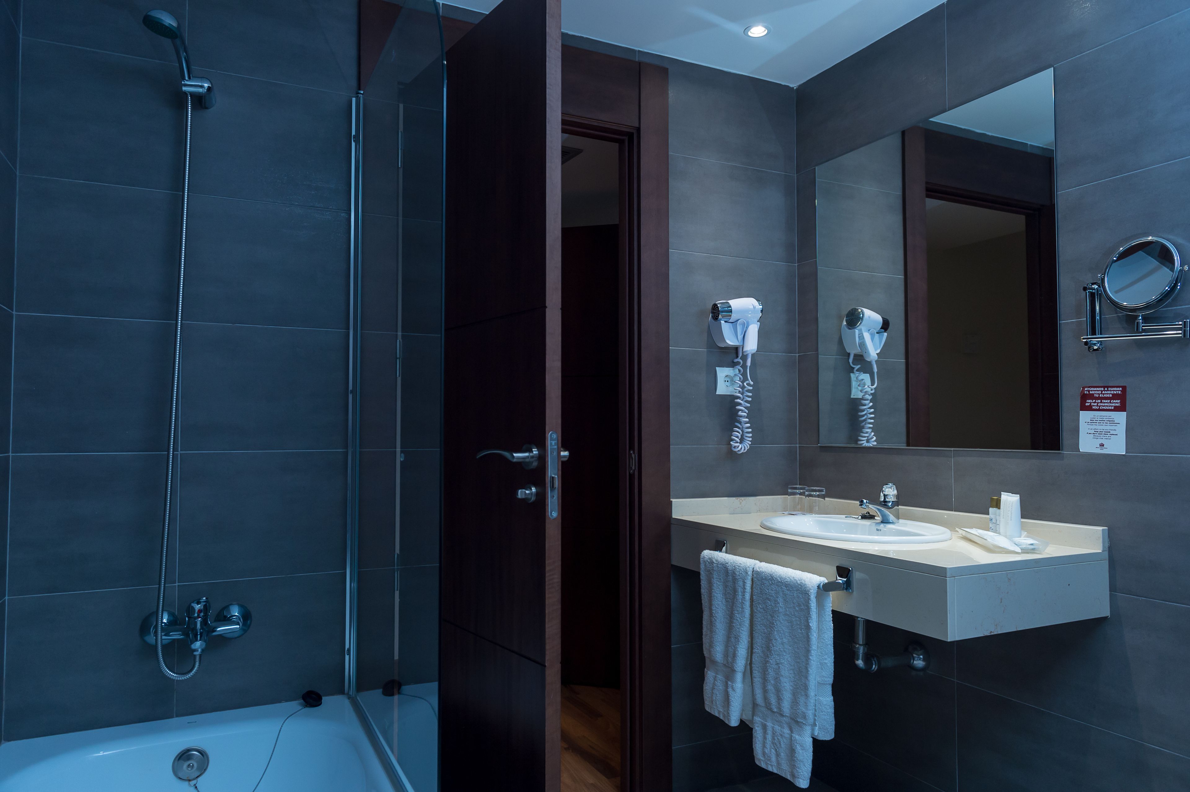 Un baño moderno con bañera, ducha, lavamanos y espejo.