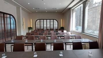 Uma sala de conferência com mesas e cadeiras, grandes janelas e vista para a cidade.
