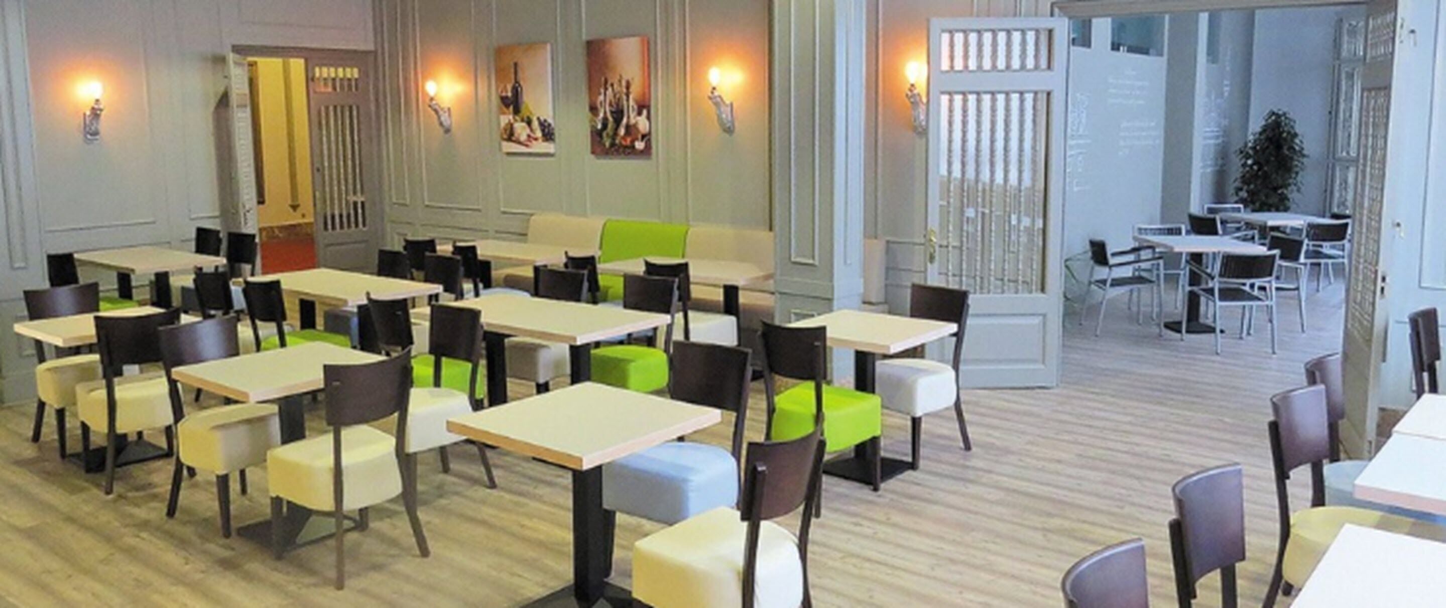 A spacious dining area with multiple tables and chairs, a bright interior, and a view of the outside.