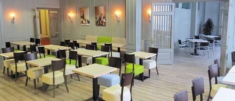 A spacious dining area with multiple tables and chairs, a bright interior, and a view of the outside.