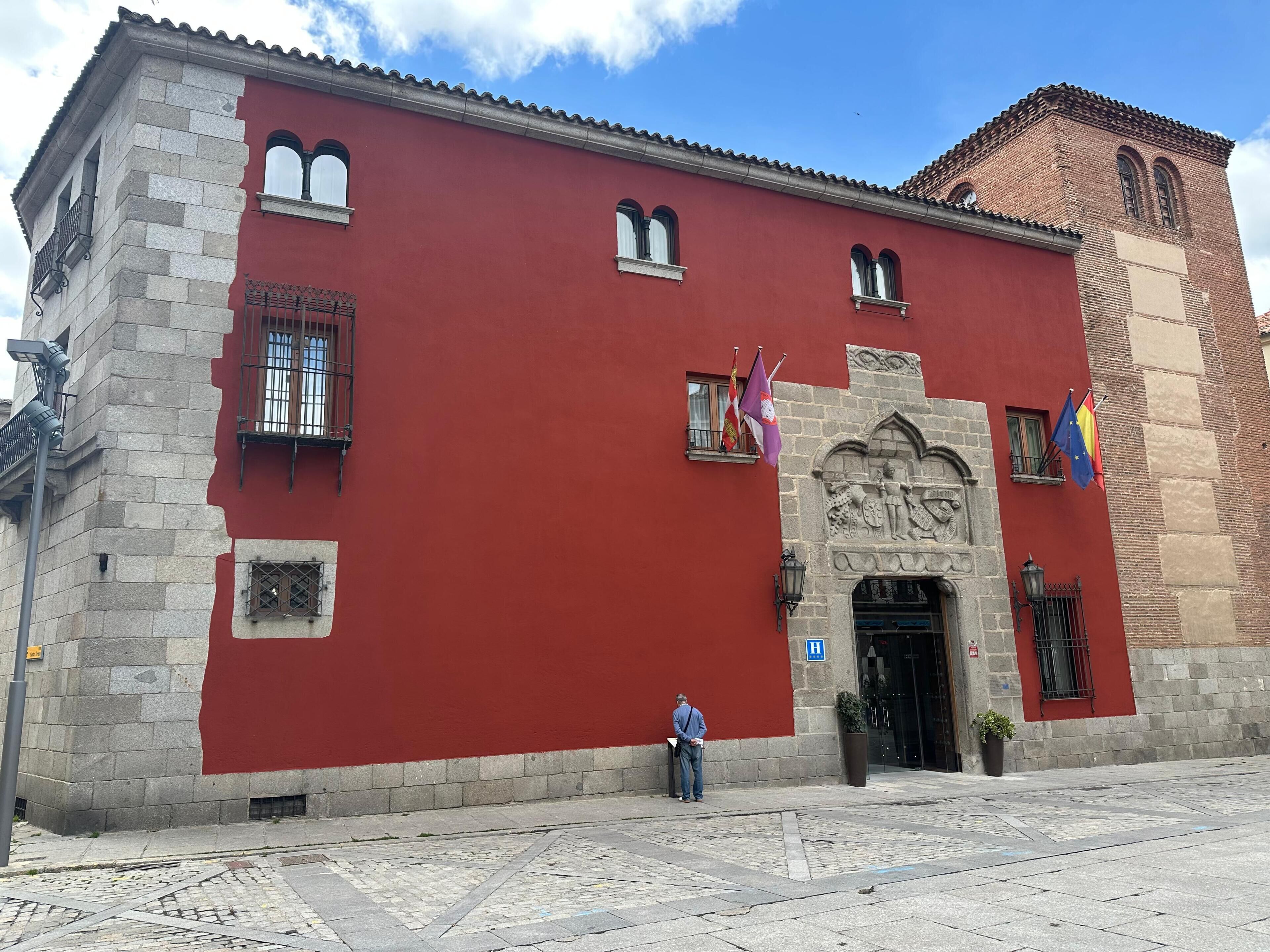 A red building with stone walls, a large entrance, and flags.
