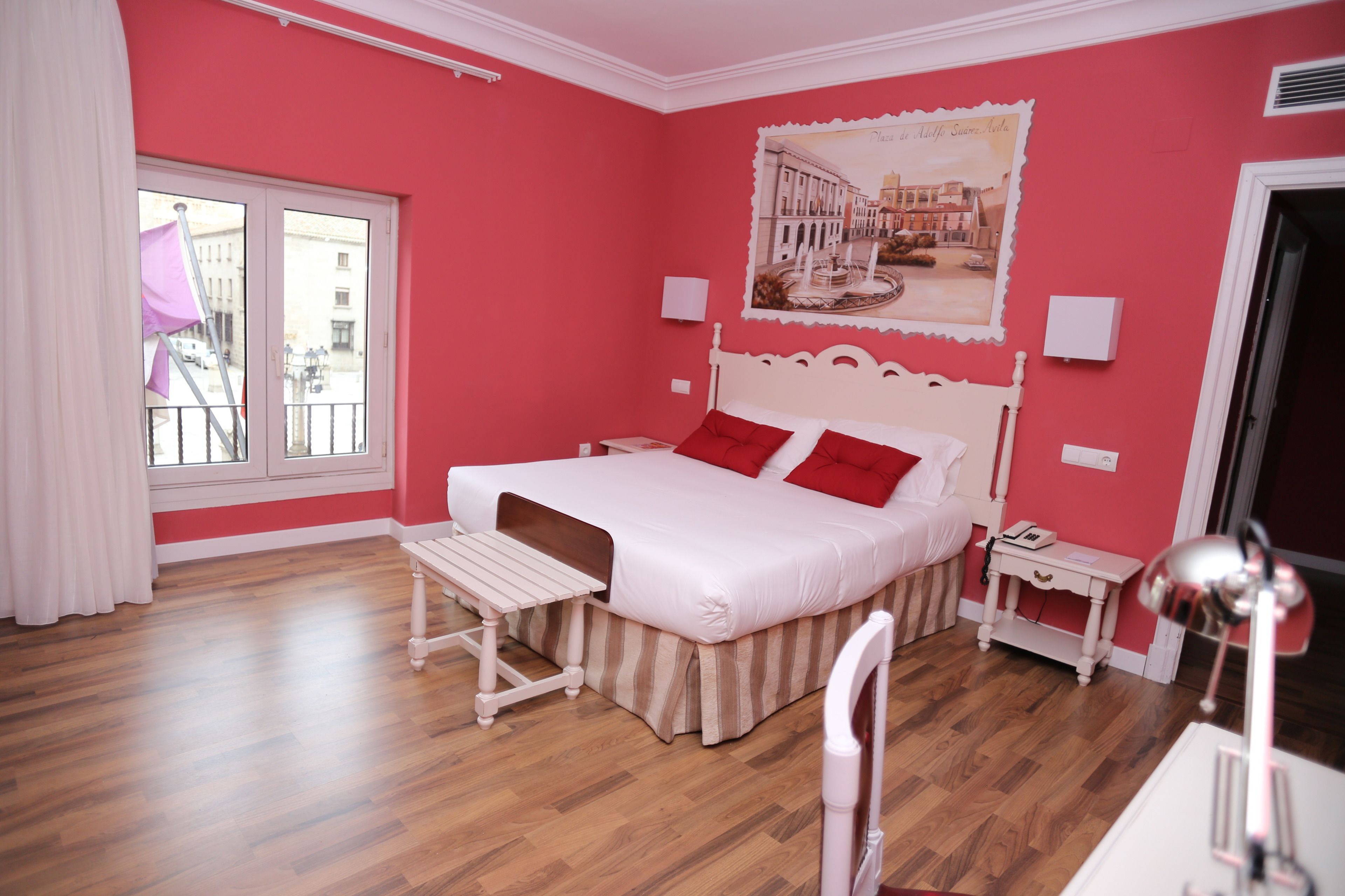 A bedroom with a bed, bedside table, chair, and a window with curtains.
