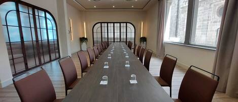 A conference room with a long table, chairs, and large windows.