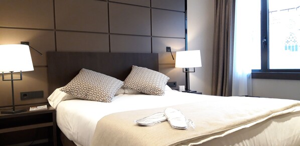 Relax in a stylish room with a large bed, two bedside tables, and a pair of slippers.