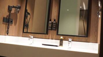 A hotel bathroom with two sinks, a mirror, a hairdryer, and towels.