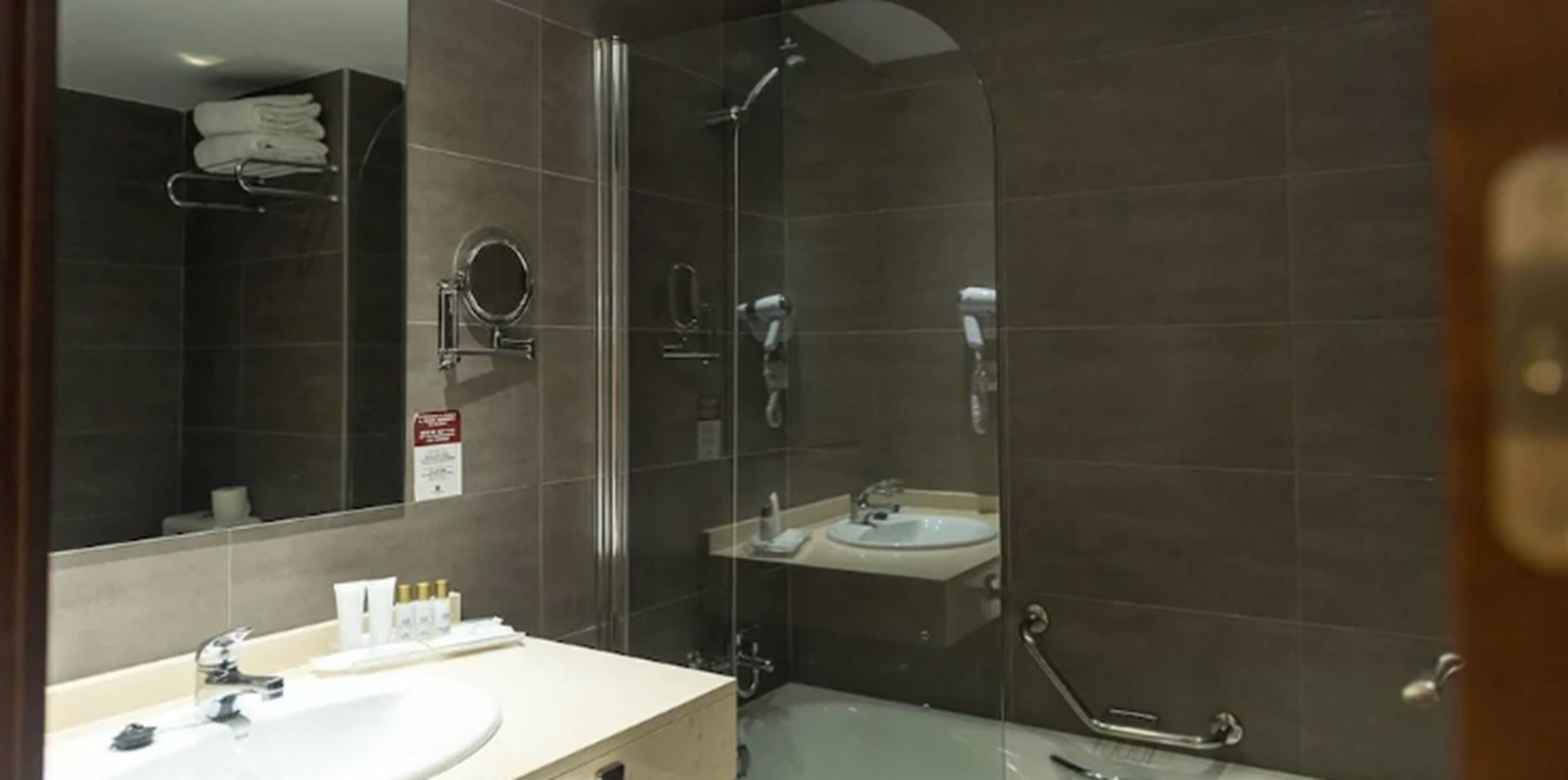 Un baño moderno con ducha de vidrio, lavamanos y espejo.