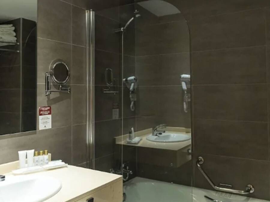 Un baño moderno con ducha de vidrio, lavamanos y espejo.