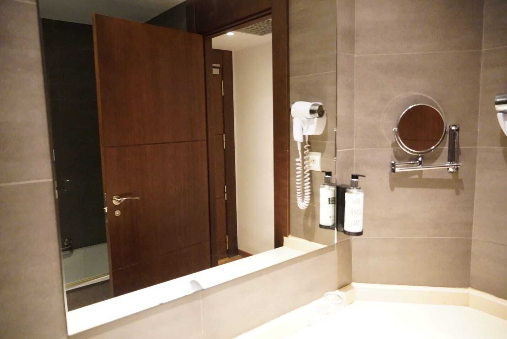 Ein Badezimmer mit einem großen Spiegel, einem Fön und zwei Shampoo-Flaschen.