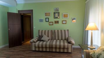 Um quarto com um sofá listrado, uma porta de madeira e uma parede com quadros.